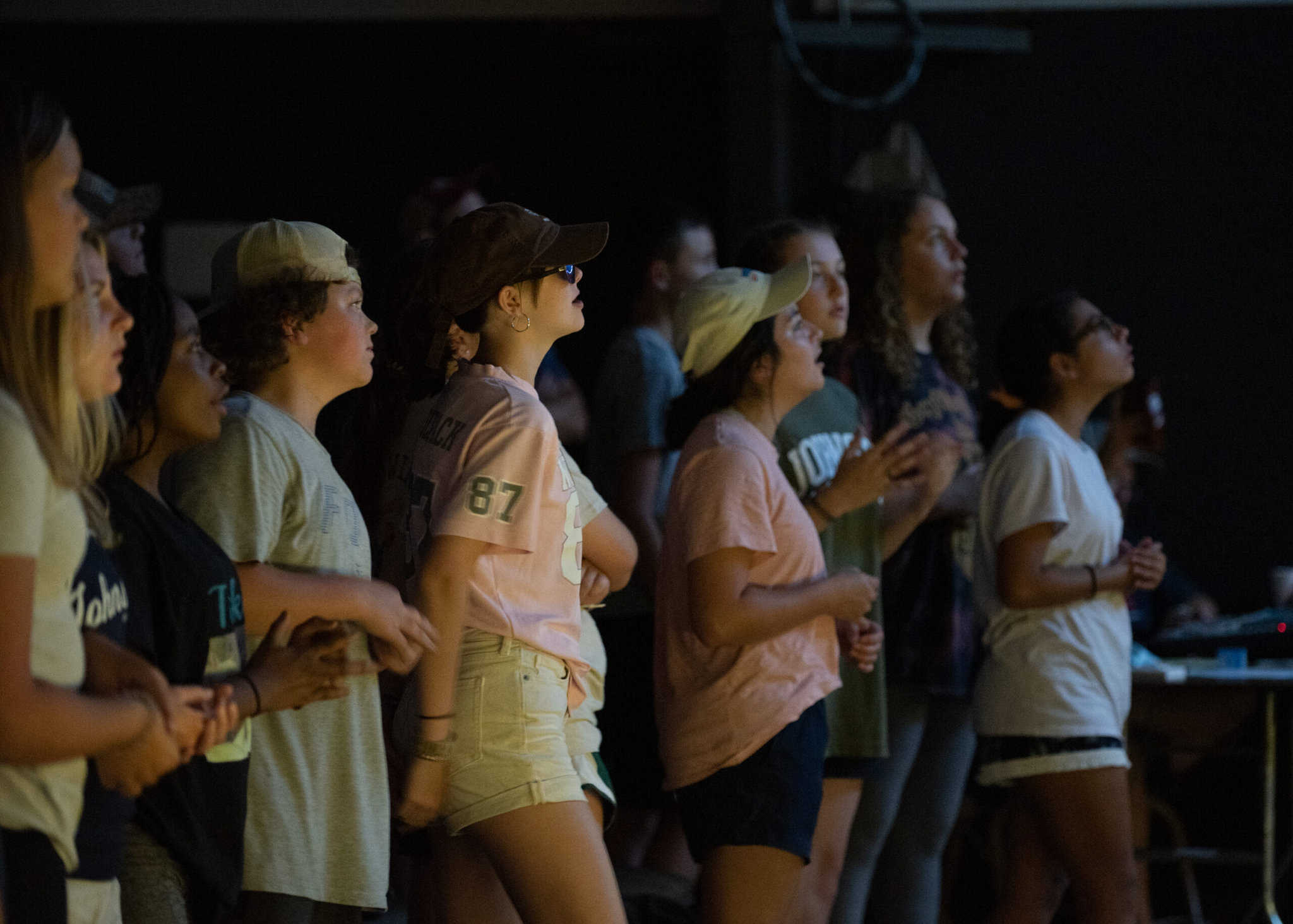 A group of young people gathered for worship in a a dimly lit space.